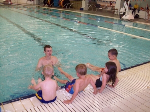 Preschoolers learn how to kick from their water safety instructor